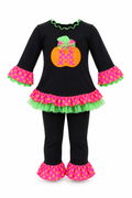 A toddler Halloween costume set consisting of a black long-sleeve top with a pink and green polka dot ruffled hem, a green ruffled neckline, and a central orange pumpkin applique with a pink bow. The set includes matching black leggings with pink and yellow polka dot ruffled cuffs.
