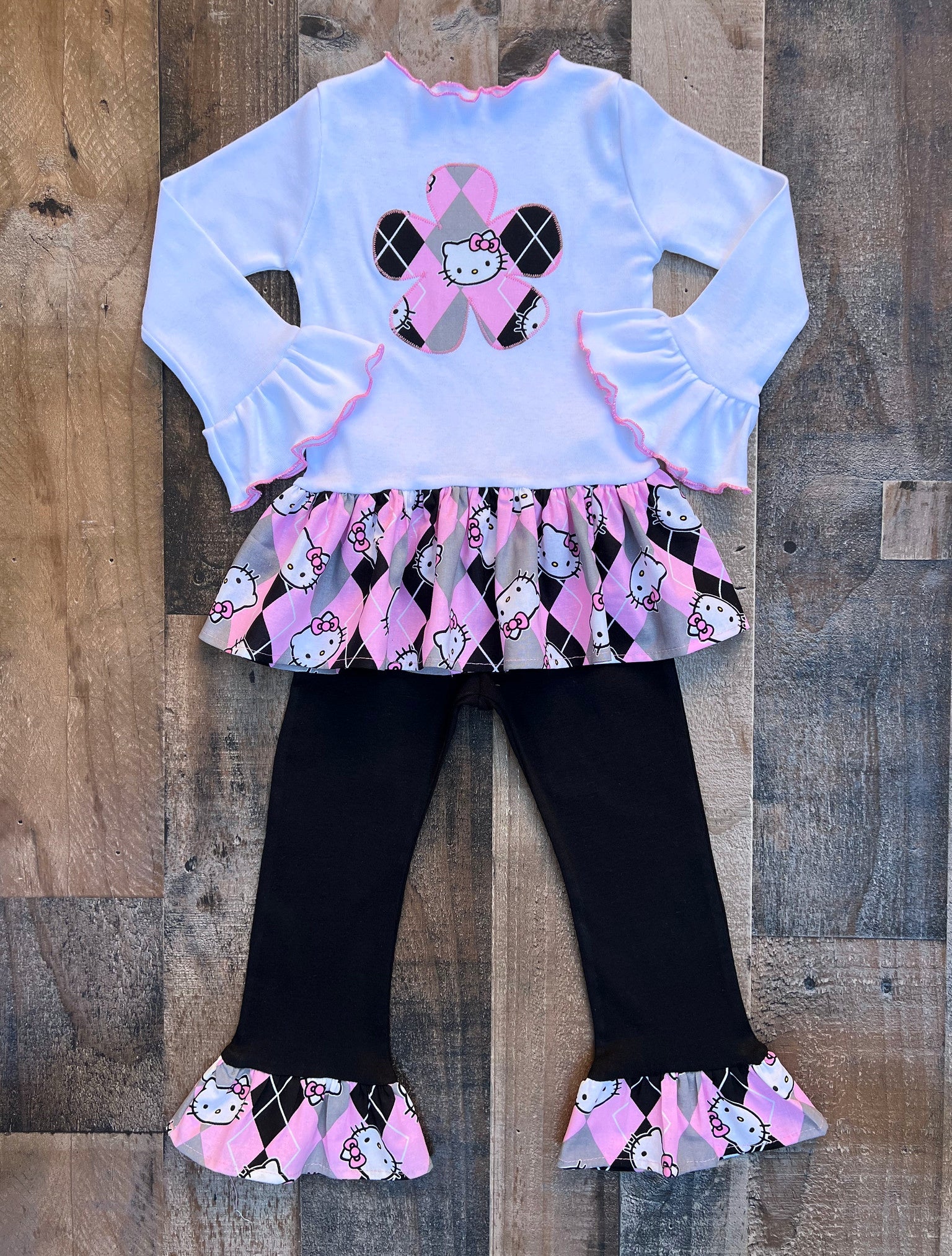 This cute Hello Kitty outfit would be perfect for a Hello Kitty theme birthday party celebration or just a fun day out in the sun. Top is long sleeved with a Hello Kitty print fabric trim. Leggings are a comfy black knit with a ruffled trim.
