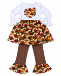 A toddler girl's two-piece autumn outfit featuring a white long-sleeve top with ruffled sleeves and a turkey print applique on the chest, paired with brown flared leggings that have matching turkey and daisy print ruffled hems.