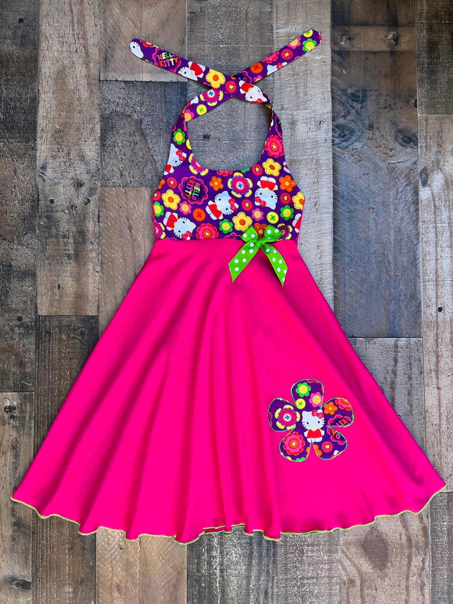 This cute Hello Kitty dress would be perfect for a Hello Kitty theme birthday party celebration or just a fun day out in the sun. Dress is halter style with a hot pink comfy knit skirt panel. Top bodice is a purple floral Hello Kitty print.
